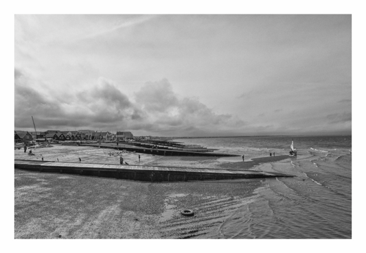 Black and white photograph of a coastal scene with a beach and ocean, Minimalist black and white fine art photograph of wooden groynes on Whitstable Beach, Kent.