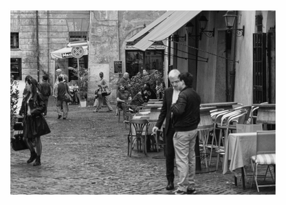 Black and white street scene with people and outdoor cafe tables, Black and white fine art street photograph of a handbag vendor carrying knock-off bags in Trastevere, Rome, Italy.