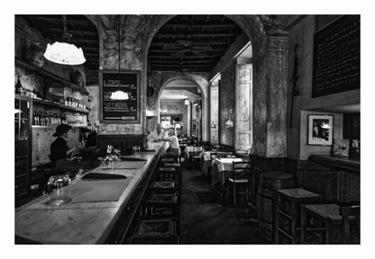 Black and white interior of a vintage-style bar with wooden counter and stools, Black and white fine art street photograph of an Italian bar in Rome, focusing on the facade's geometry and contrast.