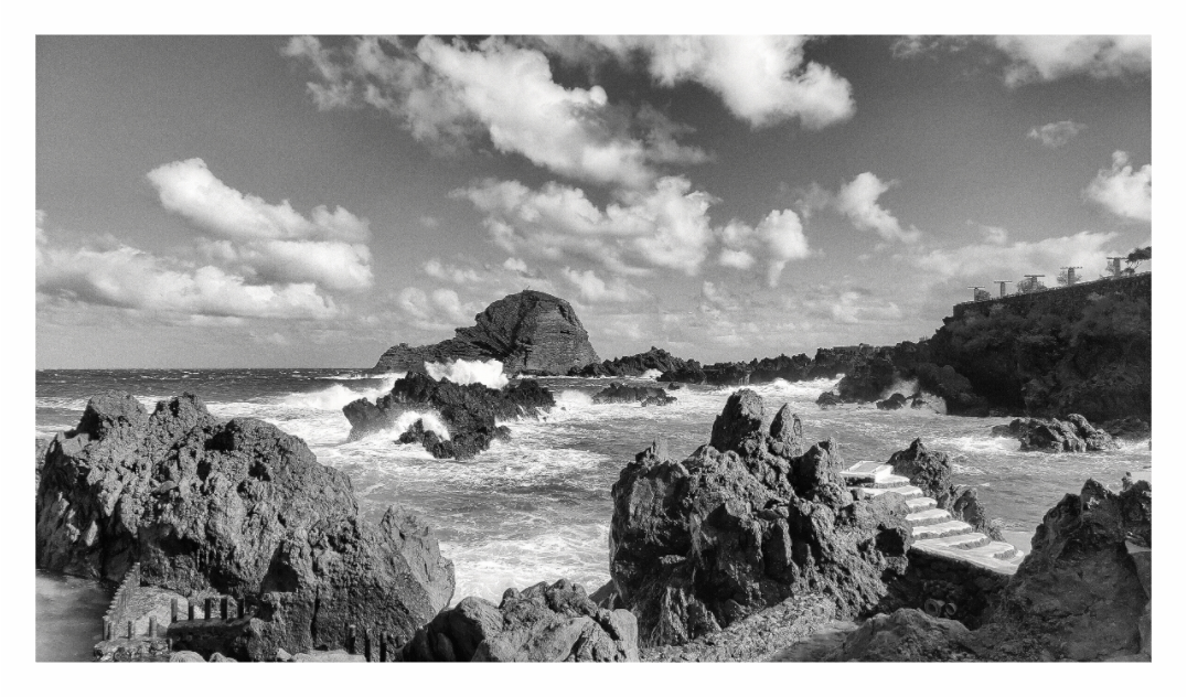 Black and white landscape of a rocky coastline with waves and clouds, Black and white fine art seascape of a rugged coastline in Madeira, Portugal, with Atlantic Ocean waves crashing against the rocks