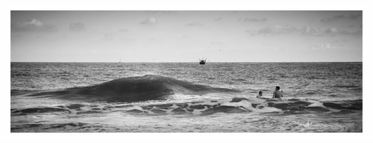 People swimming in the sea, a wave crashing, a fishing boat on the horizon, the sea ocean wave print, endless crashing surf under vast sky, moody silver coastal photography, minimalist fine art seascape, tranquil living room wall art
