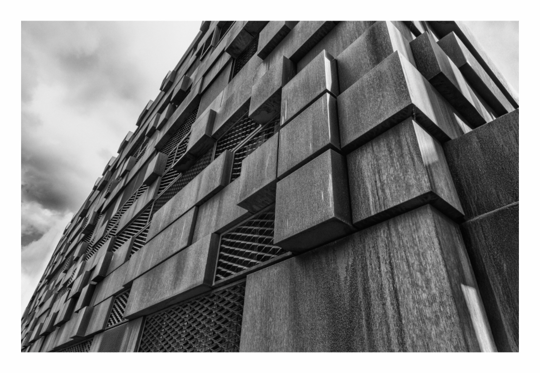 Black and white architectural photo of a modern building facade, Black and white fine art photo of modern steel cladding in Manchester, emphasizing the repetitive vertical lines and texture.