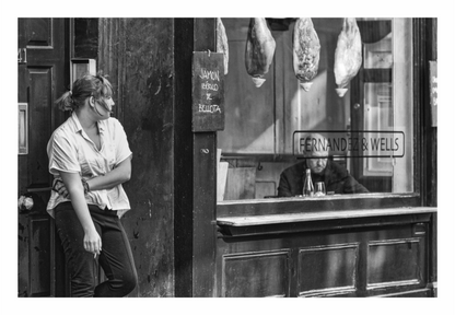 Person leaning against a wall next to a bar with 'Fernandes & Wells' sign, Black and white fine art architectural abstract print of a window detail in Soho, London. Man sitting in window, woman on a break outside shop