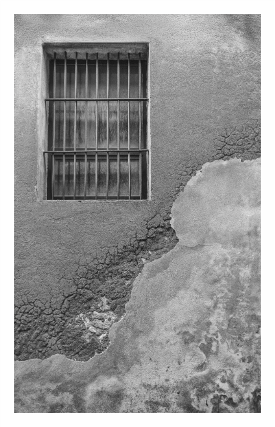 Window with bars on a textured wall. Black and white architectural print of a simple window set into a heavily textured, worn wall in a sleepy town in Lazio, Italy.
